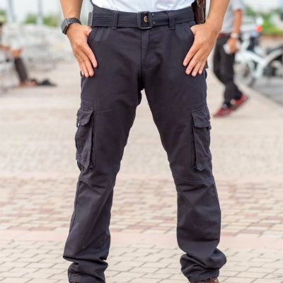 Person i forstaerkede arbejdsbukser med haenderne i lommerne udendoers