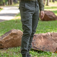 Person i komfortable lejrbukser staar udendoers i naturen