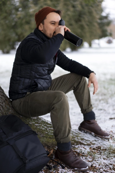 Mand i komfortable camp bukser sidder udendoers og drikker