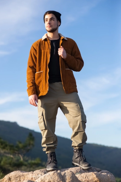 Mand i rejse nomad bukser staar paa klippe i naturen