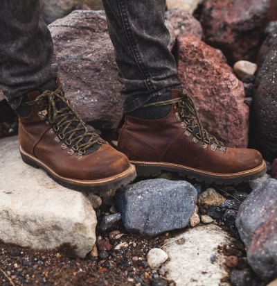 Ung hipster mand vandrer i vild natur med slidstaerke lejr-stoevler