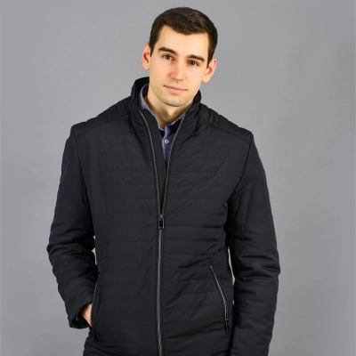 Mand i morkeblaa hoejderyg hybrid jakke med haanden i lommen