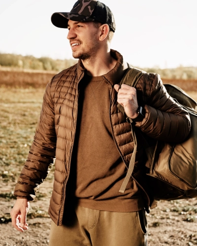 Mand i brun globetrotter rejsejakke med kasket og rygsaek