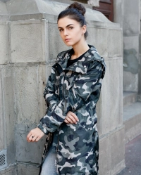 Pige klaedt i sneulv camouflage jakke foran gammel bygning