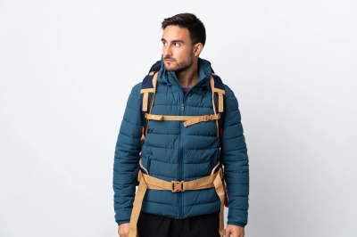 Mand med ryksaek i bla klippevaeg klatrejakke kigger til siden