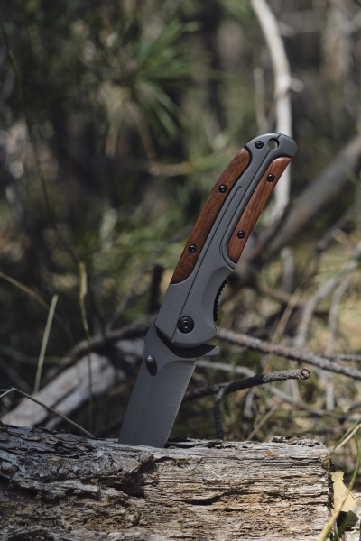 Folde taktisk overlevelseskniv med traegreb i roddent trae i skov