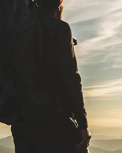 Par i backpacker udstyr der kigger ud over et bjerglandskab